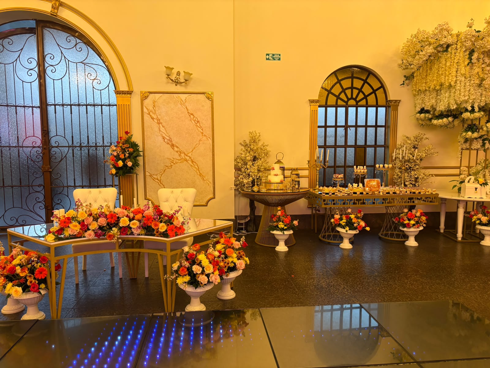 Lounge dorado con mesa de postres, torta y pista LED